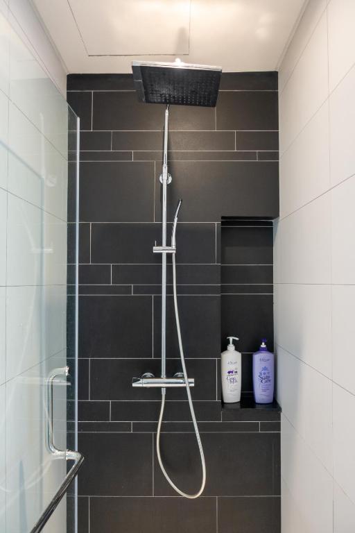 a shower in a bathroom with black tiles at Anggun Residences Luxe in Kuala Lumpur