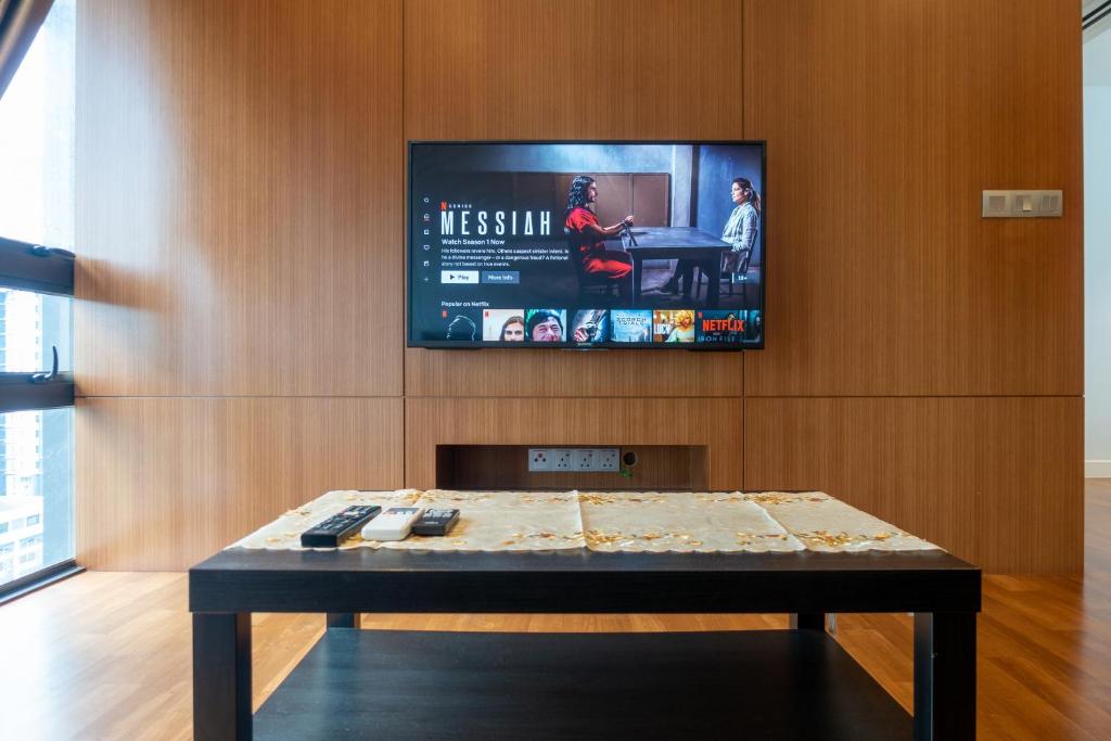 a tv on a wall with a table in a room at Anggun Residences Luxe in Kuala Lumpur