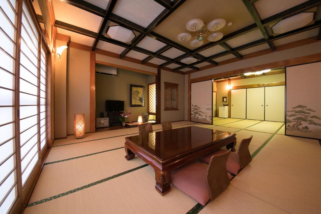 a dining room with a wooden table and chairs at Hotel Housenkaku in Beppu