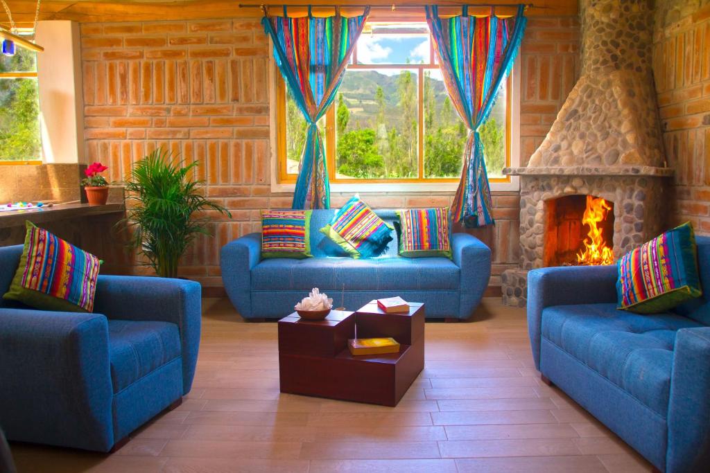 a living room with two blue couches and a fireplace at Watzara Wasi Cottage Familiar Camprestre Y Lofts en Cotacachi in Cotacachi