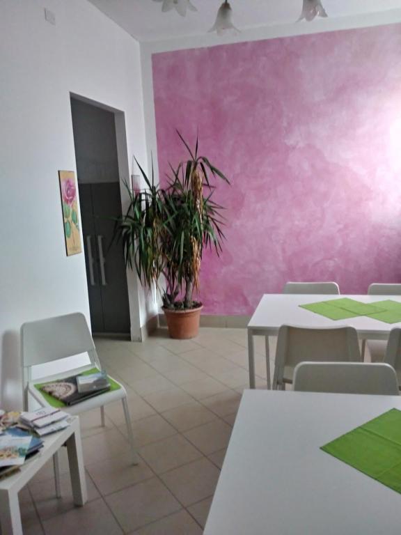 Habitación con mesas, sillas y una pared de color rosa. en ospitalità rurale, en Agliè