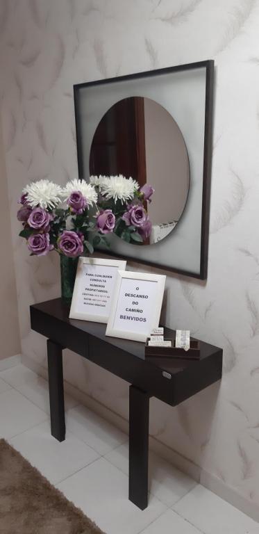 a table with a mirror and a vase of flowers at "O Descanso do Camiño" in Caldas de Reis