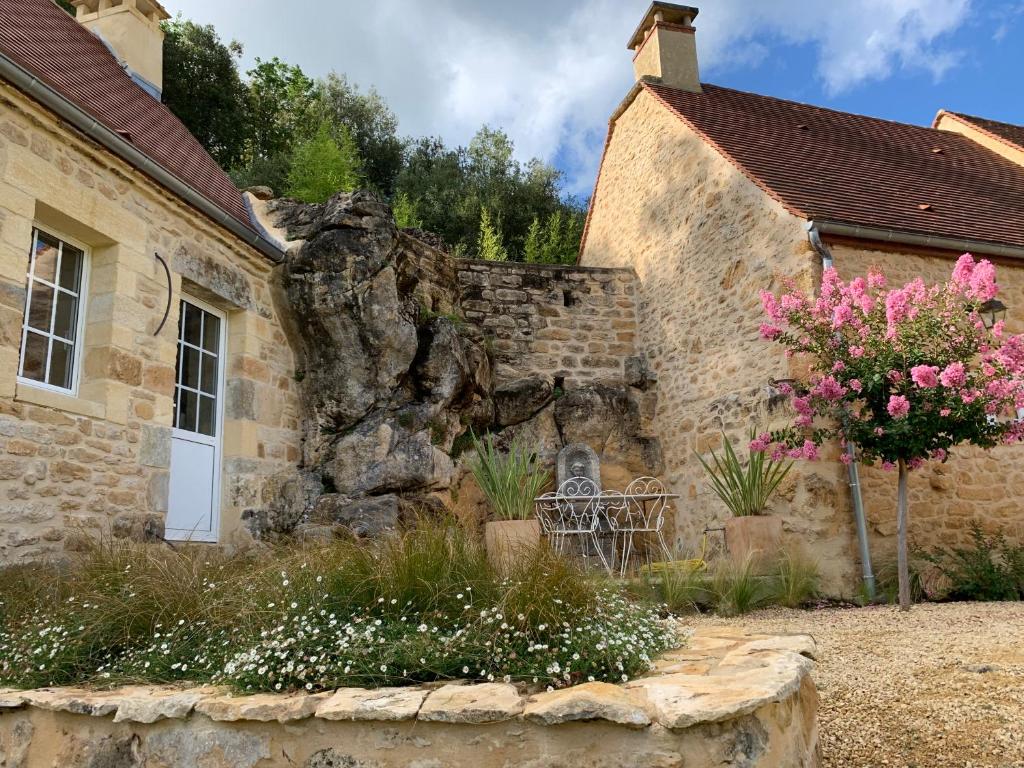 an old stone house with a stone wall and flowers at Gîte chez le Gaulois in Carsac-Aillac