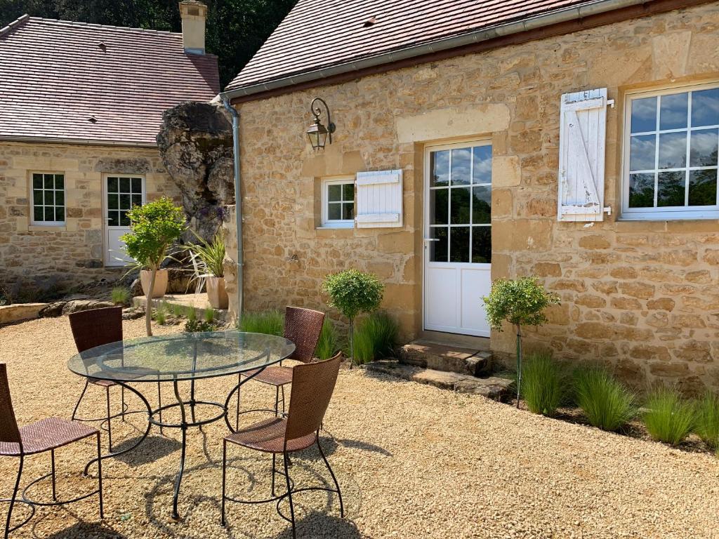 a patio with a glass table and chairs in front of a building at Gîte chez le Gaulois in Carsac-Aillac