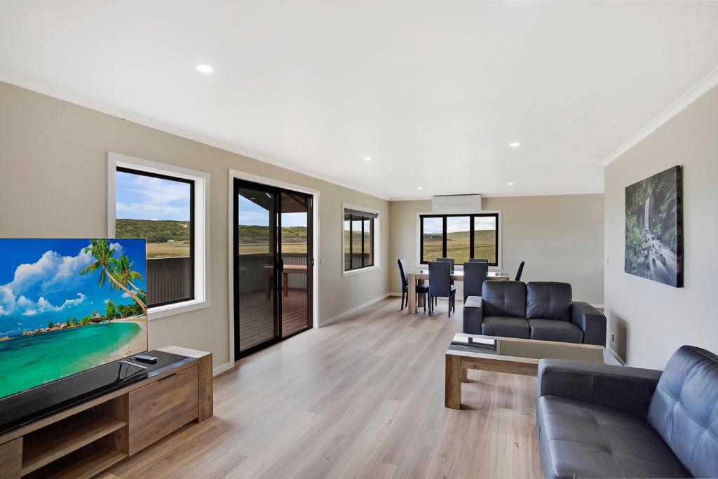 a living room with a couch and a flat screen tv at Otway coastal villas in Princetown