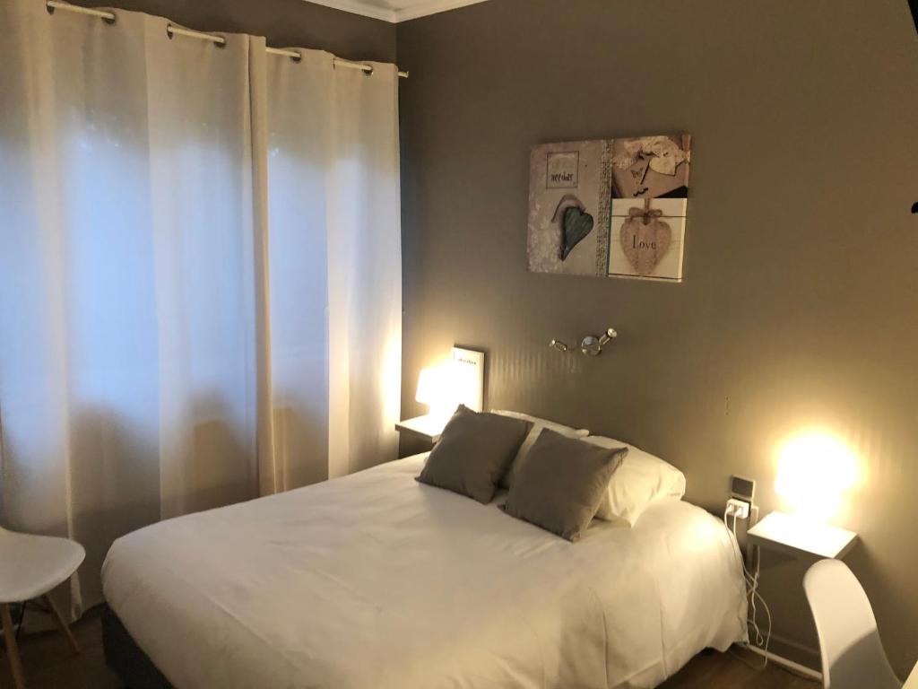 a bedroom with a large white bed with two lamps at Logis Hôtel l&#39;Abricotine in Tain-lʼHermitage