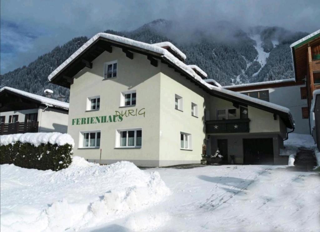 a building in the snow with mountains in the background at Ferienhaus Durig in Gaschurn