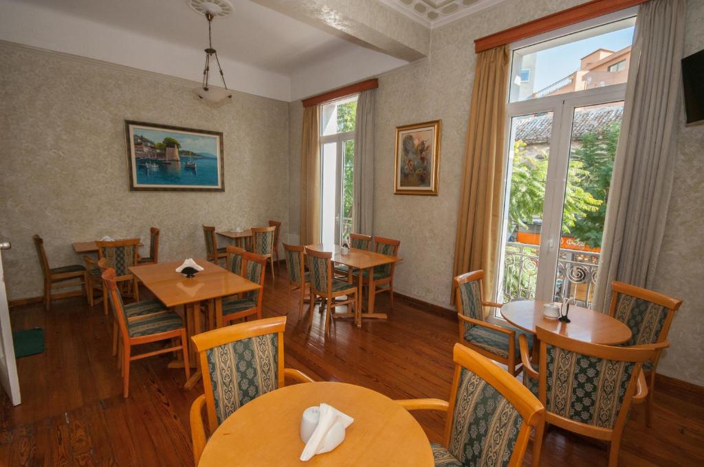 a restaurant with wooden tables and chairs and windows at Cecil Hotel in Athens