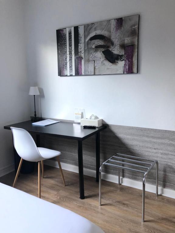 a desk and chair in a room with a picture at Logis Hôtel l&#39;Abricotine in Tain-lʼHermitage