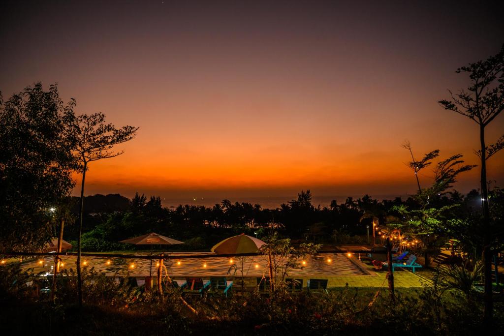 een zonsondergang bij een resort met een zwembad en verlichting bij Lover View Pool Bar & Bungalows in Ngwesaung