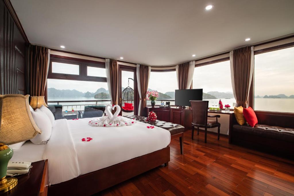 a bedroom with a large white bed and a living room at Dora Cruise in Ha Long