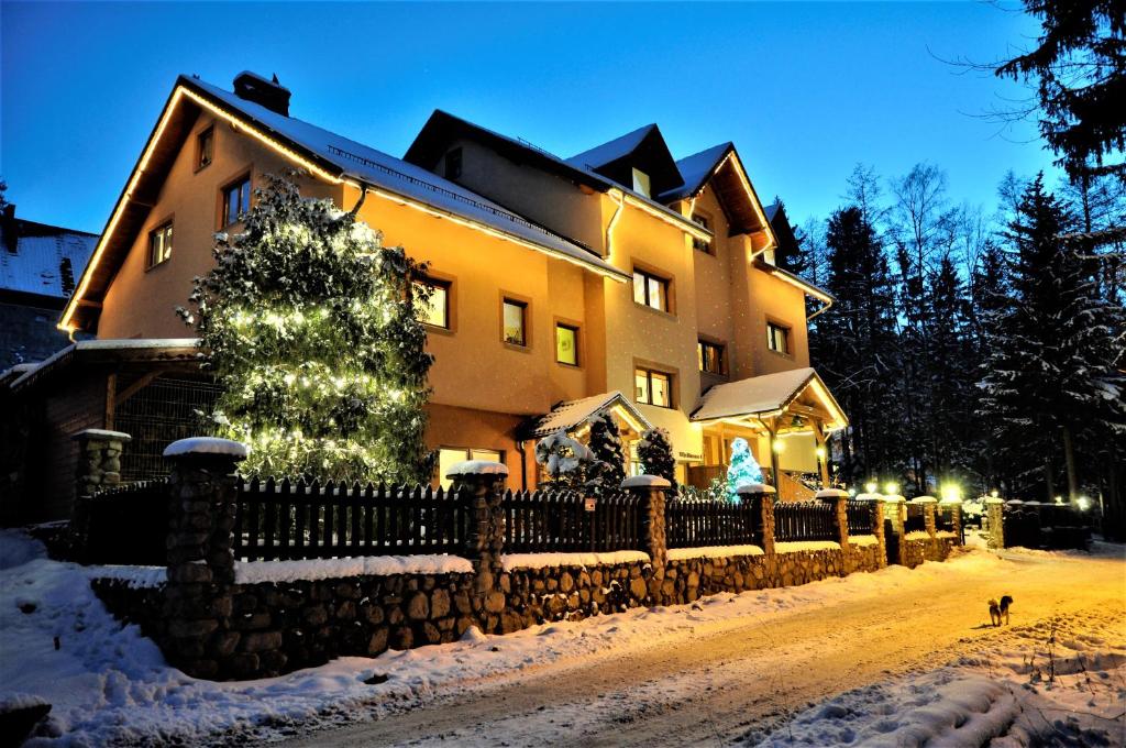 una casa con un árbol de Navidad en una calle nevada en Willa Luna, en Karpacz