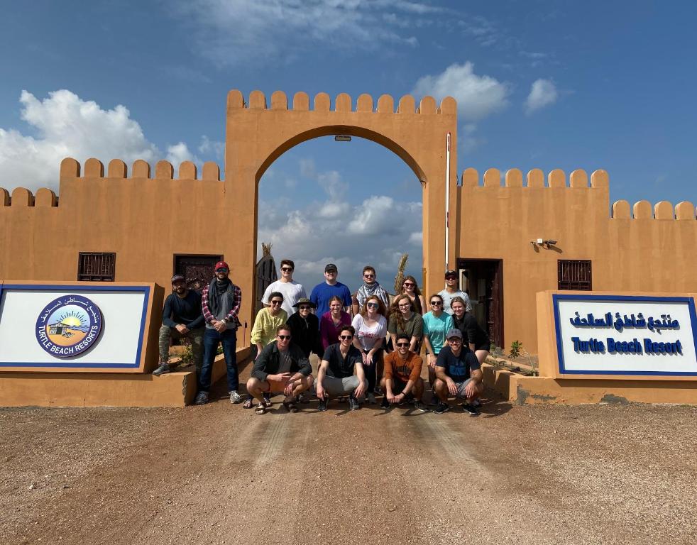 a group of people posing in front of an arch at Turtle Beach Resort in Al Ḩadd