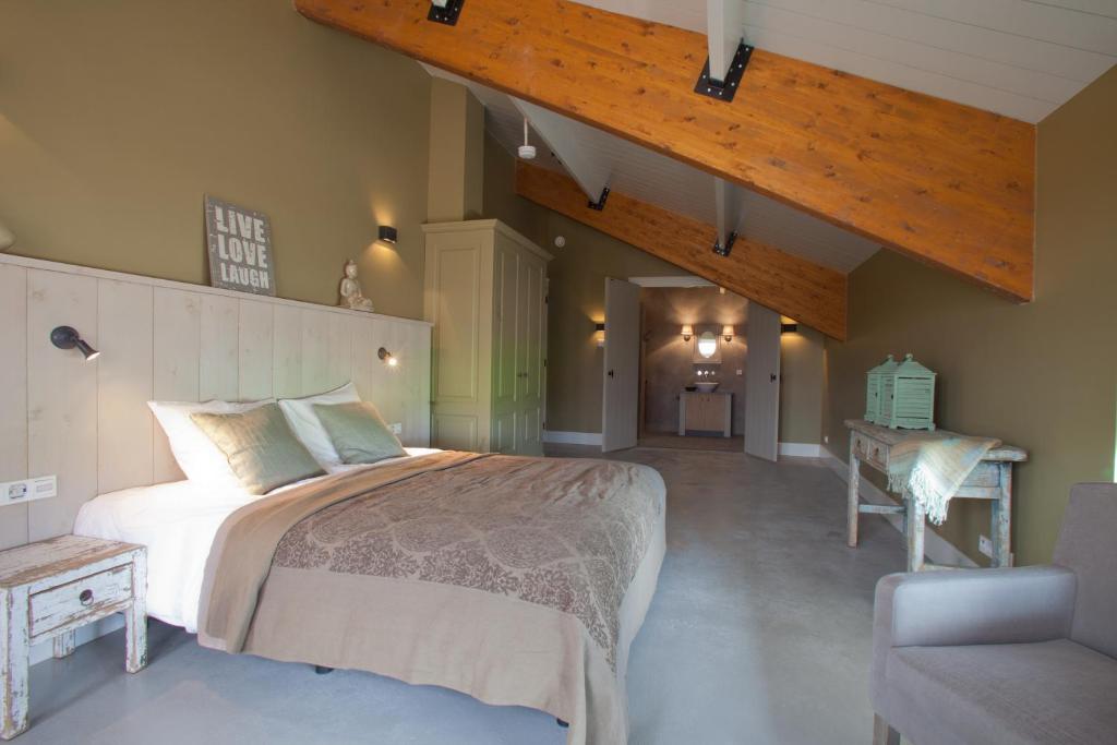 a bedroom with a large bed and a chair at Erve 't Hacht in Ane