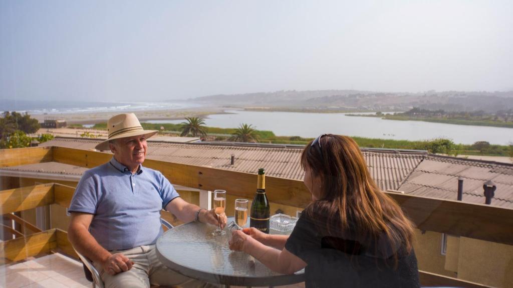 un homme et une femme assis à une table avec des verres à vin dans l'établissement Riomar Apart Hotel, à Concón