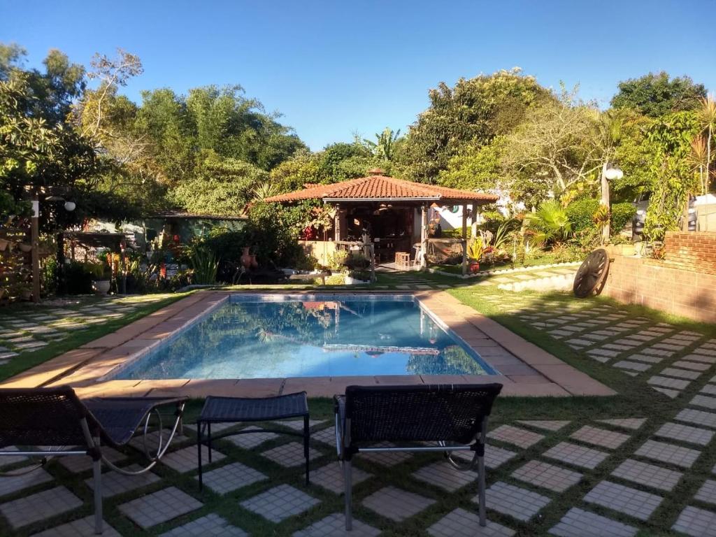 a swimming pool with two chairs and a gazebo at Pousada Guinda DIAMANTINA -MG in Diamantina