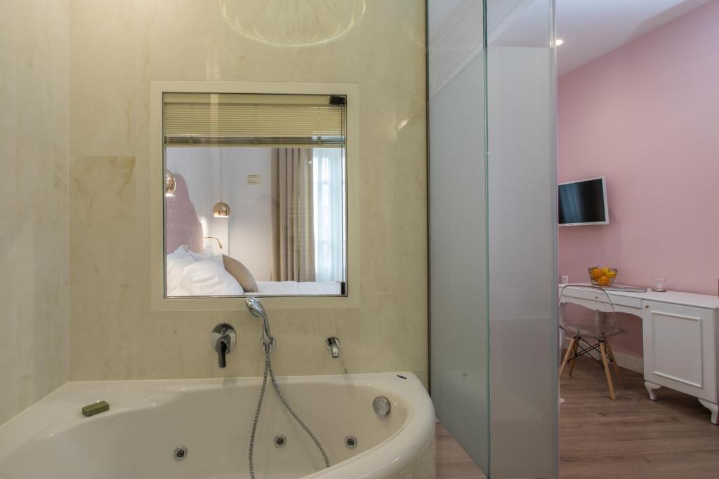 a bath tub in a bathroom with a mirror at Bahar Boutique Hotel in Thessaloniki