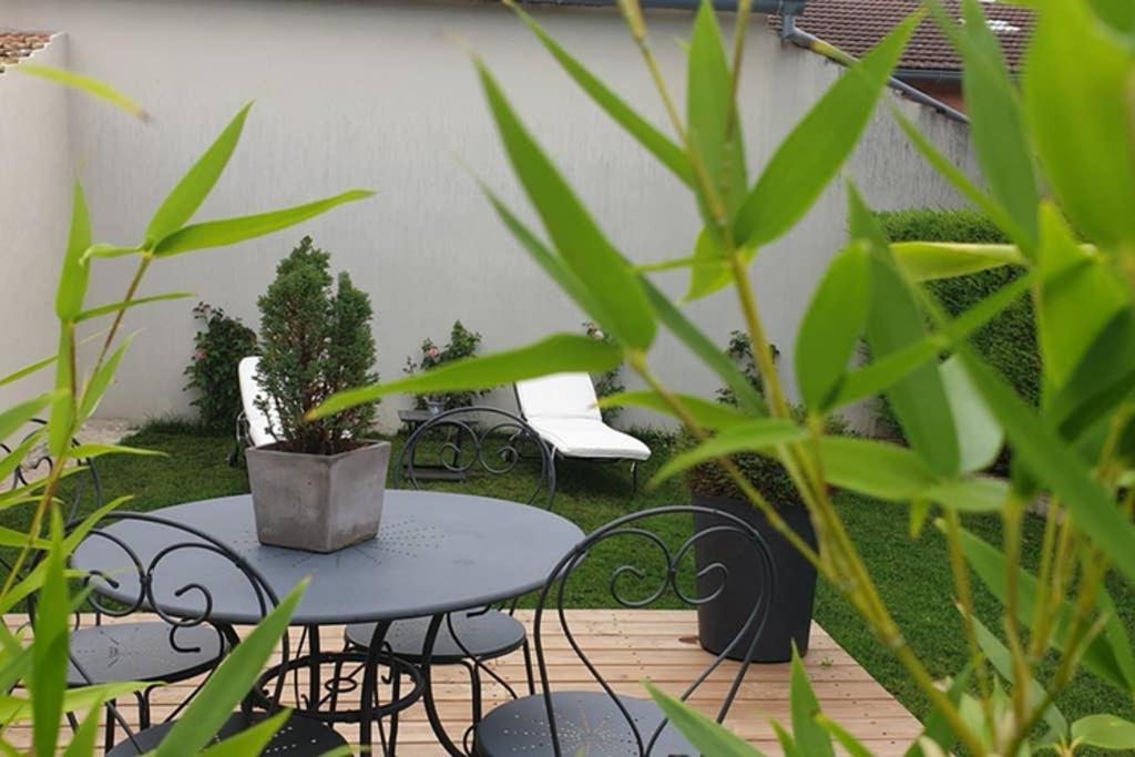 eine Terrasse mit einem Tisch, Stühlen und Pflanzen in der Unterkunft clos des mûriers in Beaune