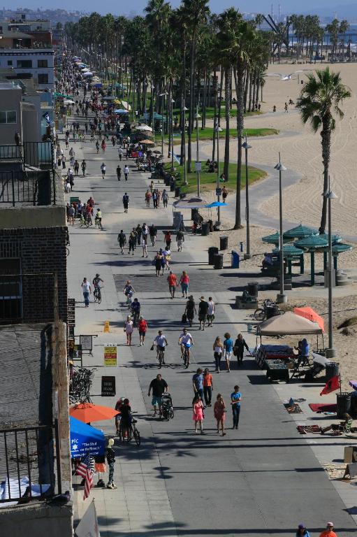 a group of people walking on a sidewalk near the beach at Venice Suites in Los Angeles
