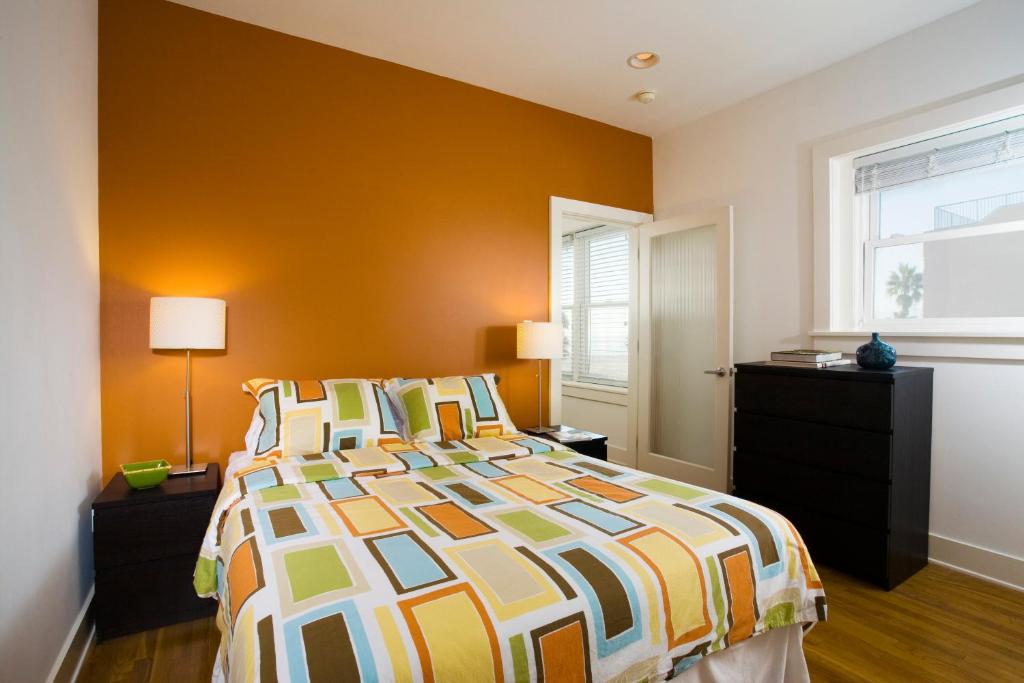 a bedroom with a bed with an orange wall at Venice Suites in Los Angeles