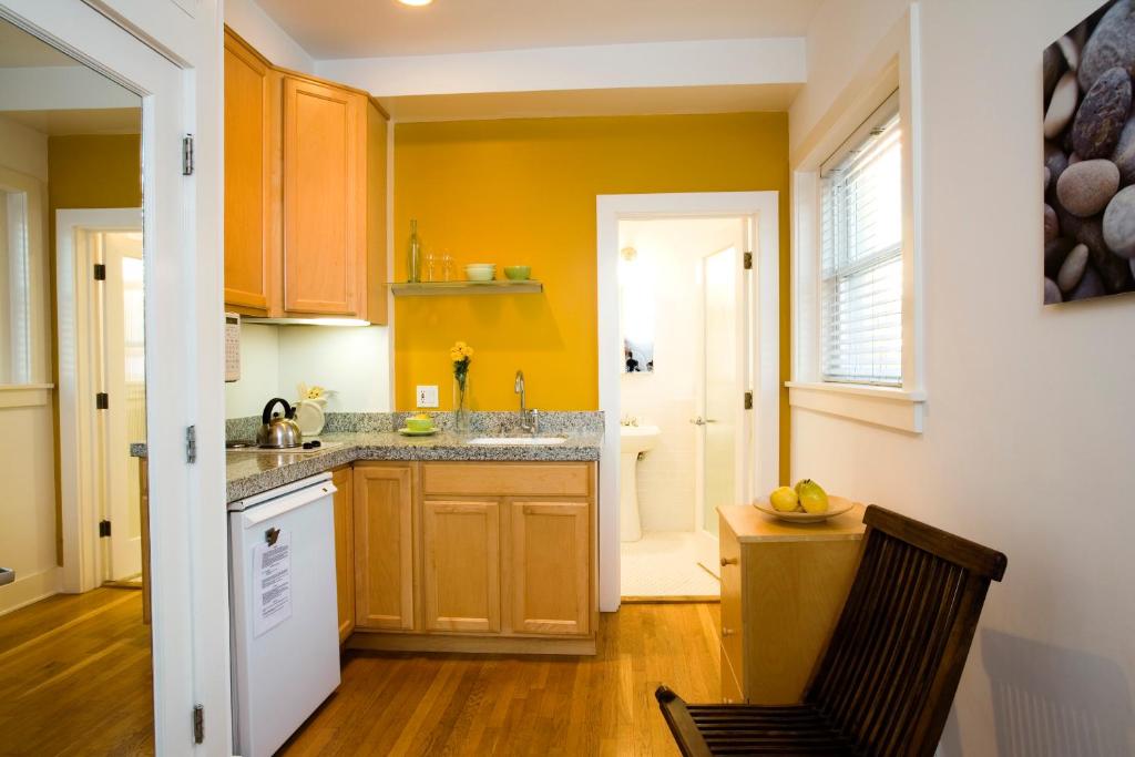 a kitchen with yellow walls and a sink and a chair at Venice Suites in Los Angeles