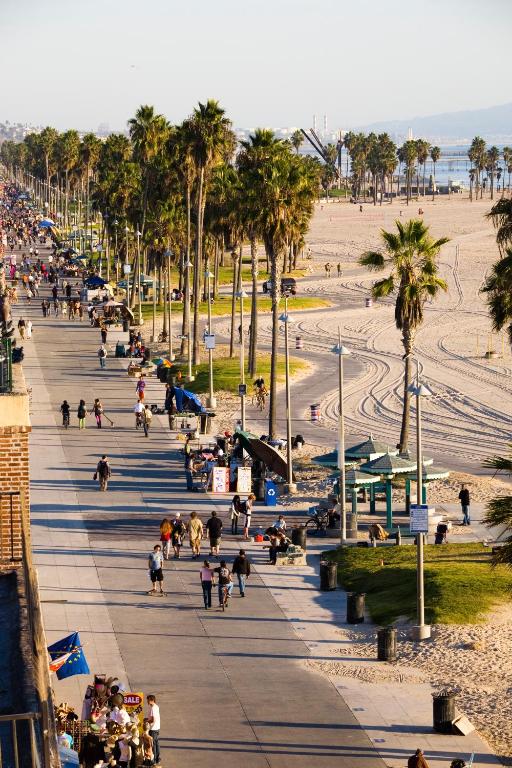a group of people walking on a sidewalk near a beach at Venice Suites in Los Angeles