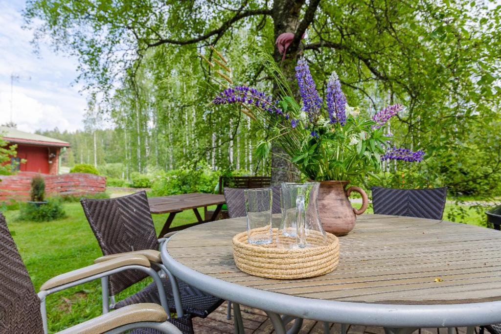 a wooden table with a vase of flowers on it at Poppelstrand Nuuksio, Pet friendly guest apartment in Nuuksio