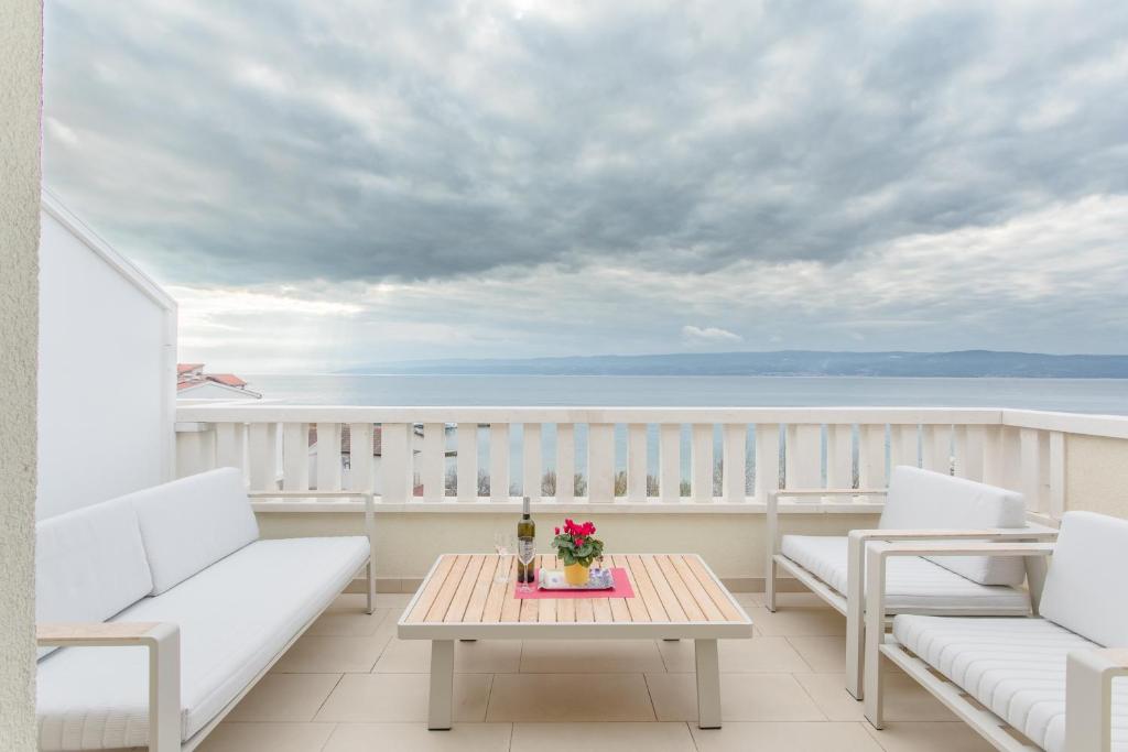 uma varanda com cadeiras brancas e uma mesa com flores em Apartments Kadenca em Omiš
