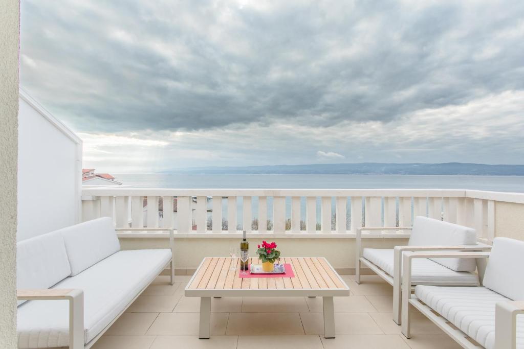 a balcony with white chairs and a table with flowers on it at Apartments Kadenca in Omiš
