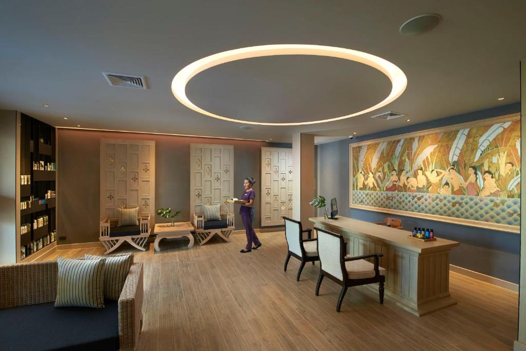 a woman standing in a lobby with a painting on the wall at Amari Vogue Krabi in Tab Kaek Beach