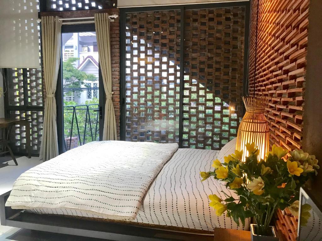 a bedroom with a bed with a window and a vase of flowers at Ngói house in Da Nang