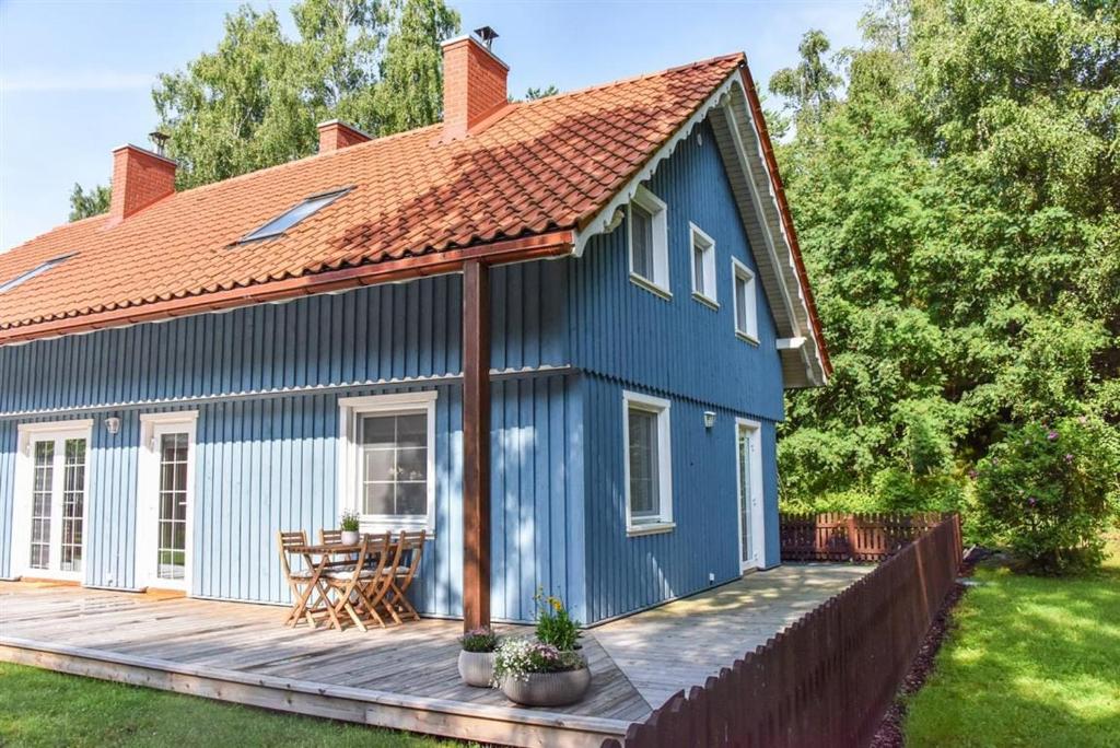 a blue house with a wooden deck in a yard at Prie kopos in Preila