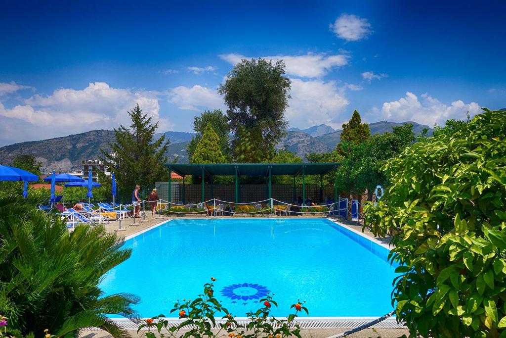 een groot blauw zwembad met bergen op de achtergrond bij Hotel Girasole in Sorrento