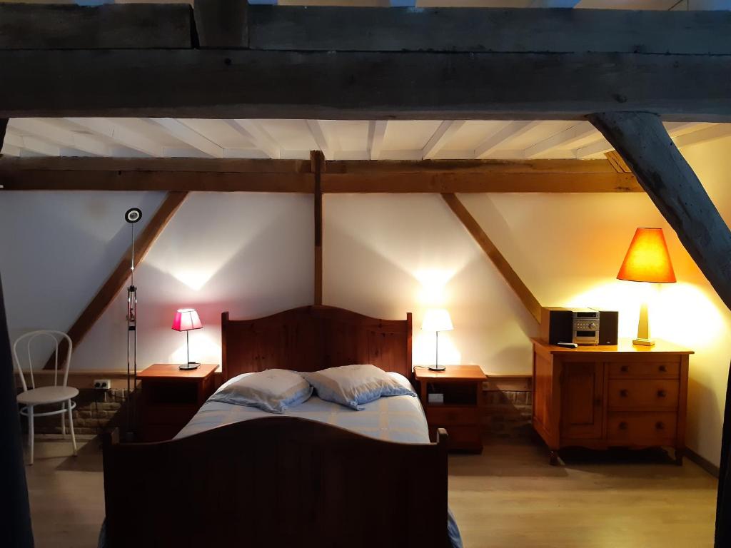 an attic bedroom with a bed and two lamps at Logement à la ferme in Hangest-en-Santerre