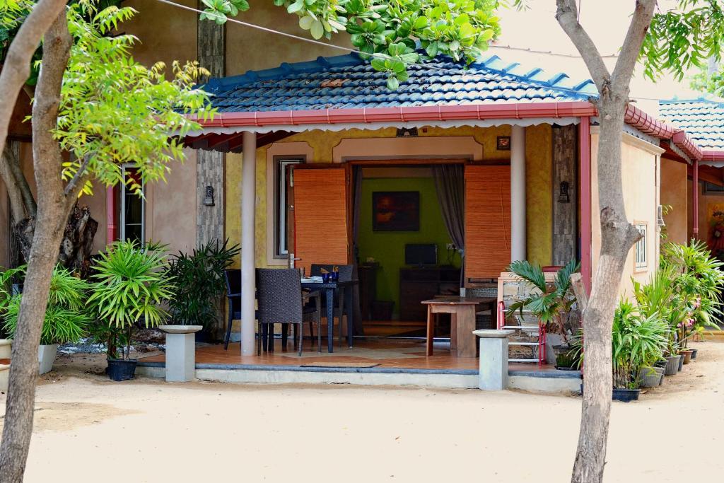 een huis met een veranda met een tafel ervoor bij Cocoville in Pasikuda