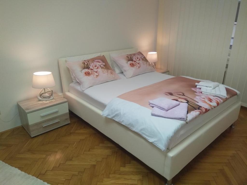 uma cama branca com almofadas cor-de-rosa e toalhas em APARTMAN S.ANTONIO em Zagreb
