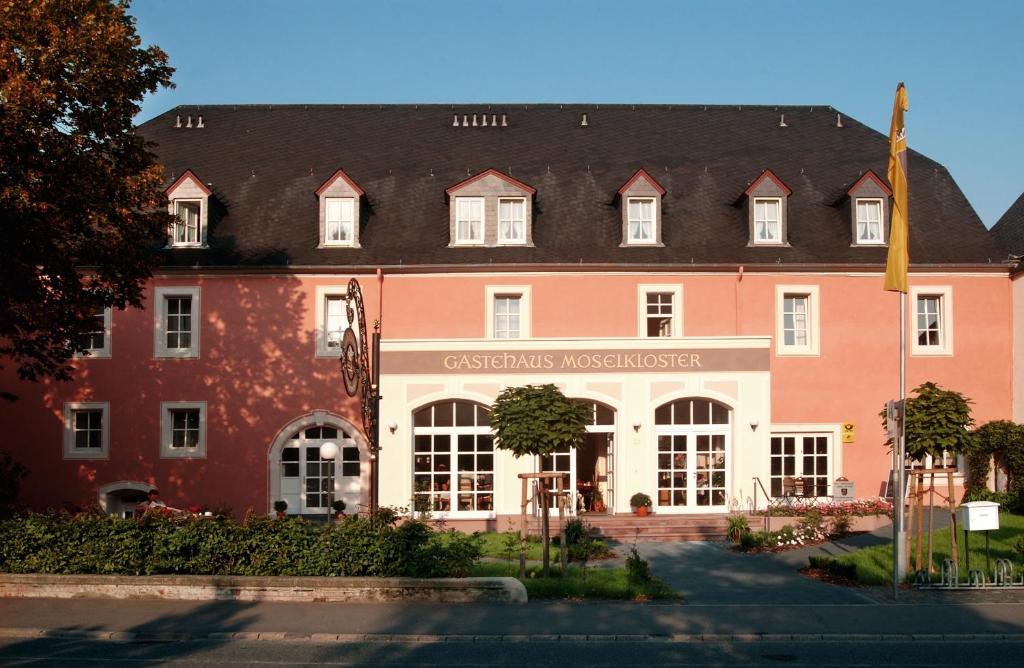 ein großes rotes Gebäude mit schwarzem Dach in der Unterkunft Gästehaus Moselkloster in Trittenheim