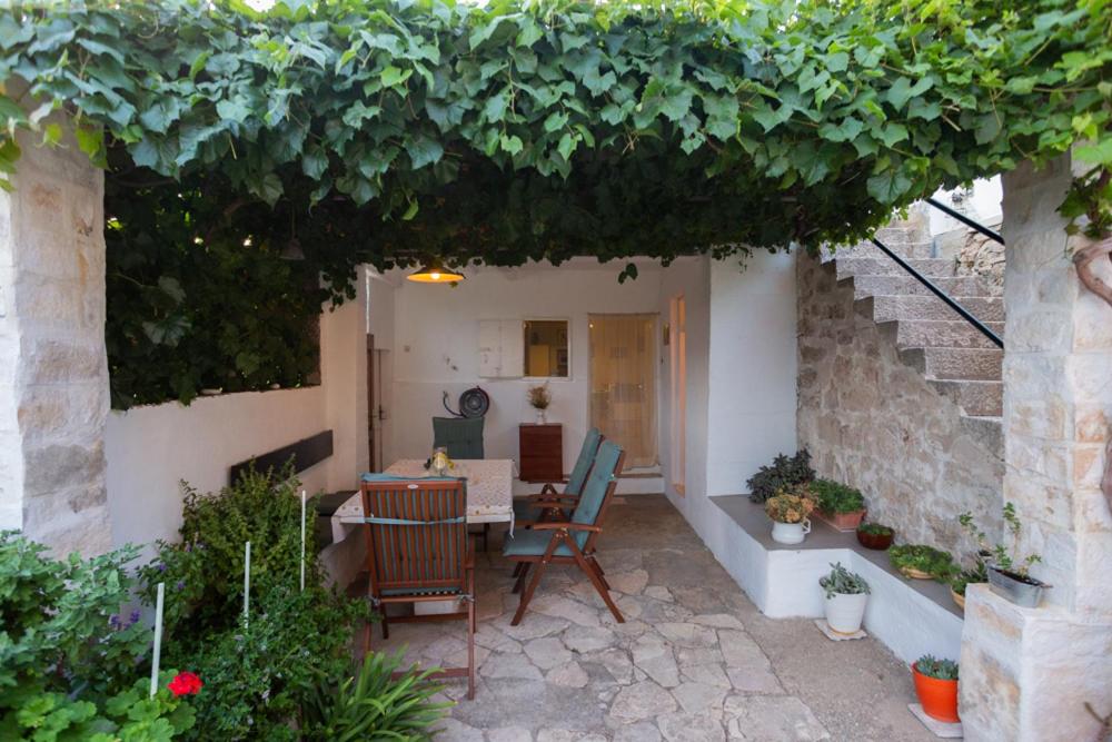 a patio with a table and chairs under an arch at Holiday Home Burba in Komiža