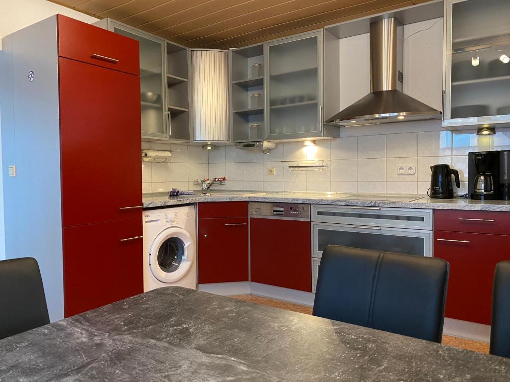 a kitchen with red cabinets and a washing machine at SAD141 - Helle Monteurwohnung mit Balkon in Schwandorf in Schwandorf in Bayern