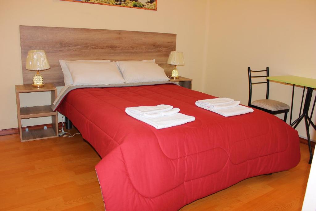 Una cama roja con dos toallas encima. en Holidays Hostel Arequipa en Arequipa