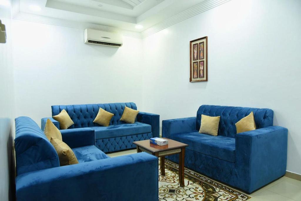 شقق جنان المفروشة Jenaan Apartments في نجران: غرفة معيشة مع كنبتين زرقاوين وطاولة