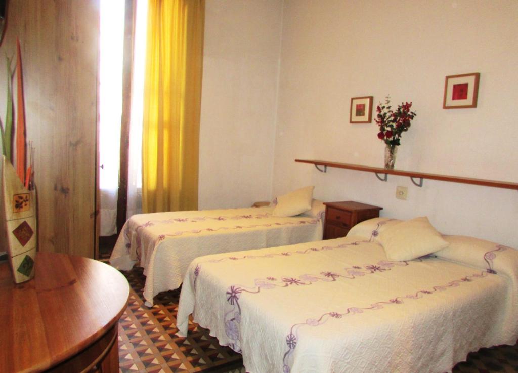 バルセロナにあるオスタル リマのベッド2台とテーブルが備わるホテルルームです。