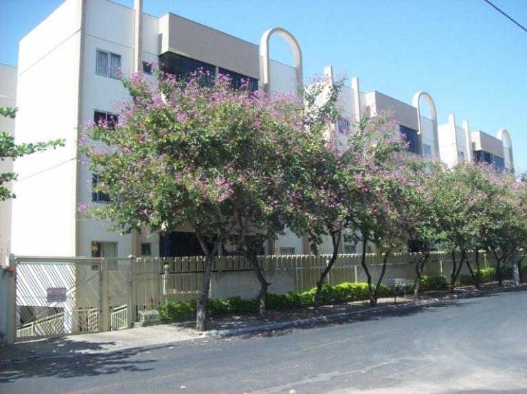 una fila de árboles con flores rosas delante de un edificio en Residencial Varanda dos Buritis, en Caldas Novas