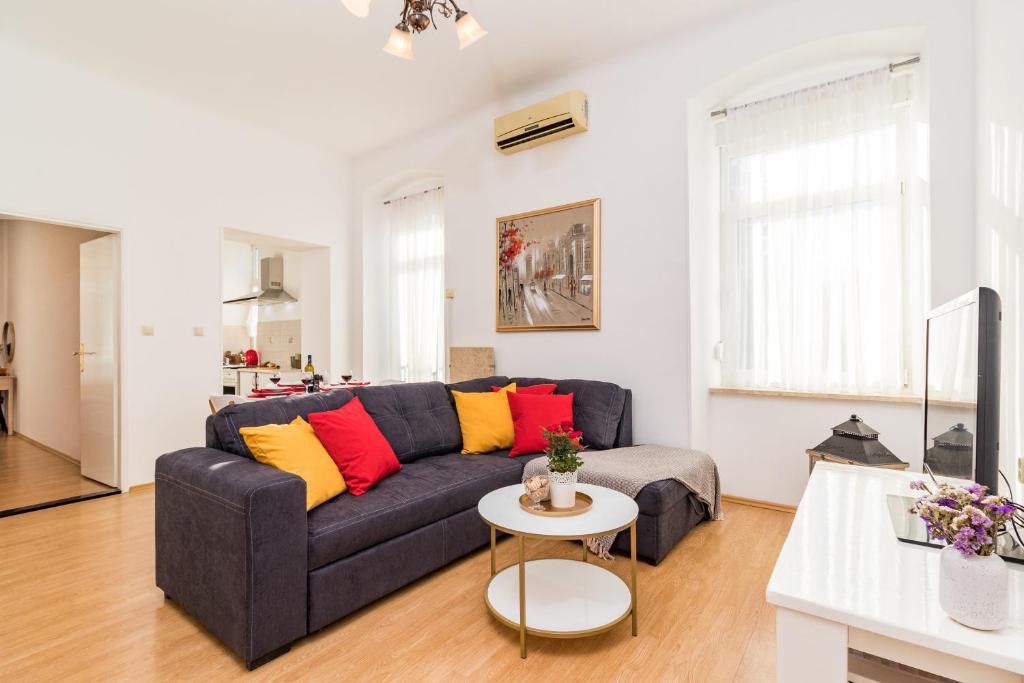 ein Wohnzimmer mit einem blauen Sofa und bunten Kissen in der Unterkunft Apartman Lussi in Pula