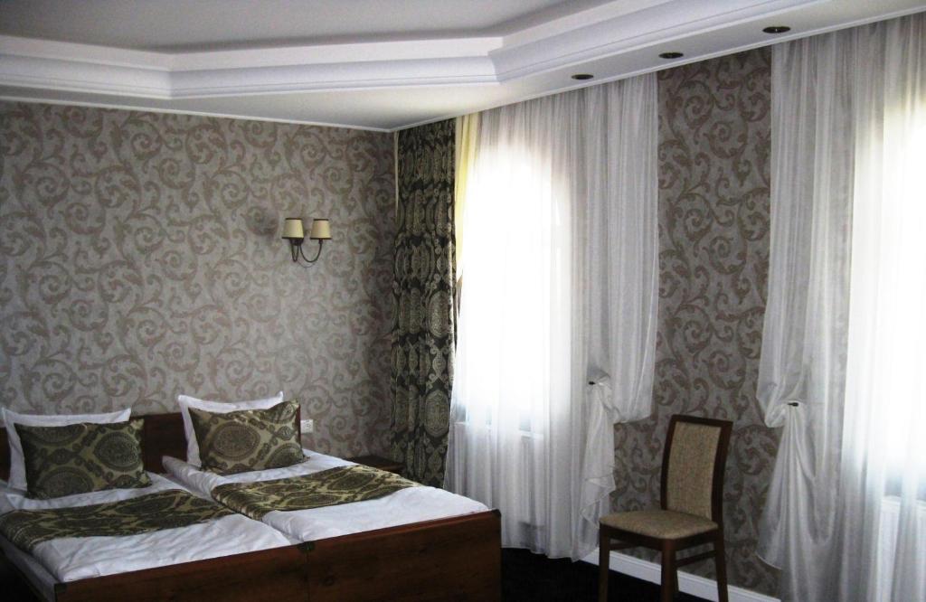 a bedroom with a bed and a chair and a window at Kera Hotel in Nesterenki