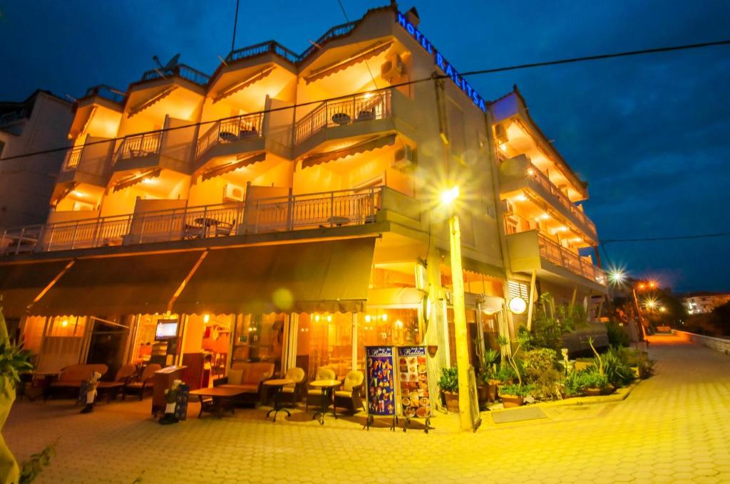 a large yellow building with a balcony at night at Hotel Ralitsa in Limenaria