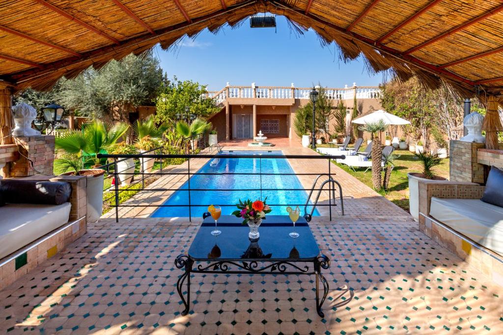 a swimming pool with a table in front of a house at Villa Ayche in Marrakech