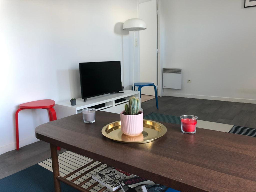 een woonkamer met een tafel en een televisie bij Joie Paris Parc Expo - Issy Les Moulineaux in Issy-les-Moulineaux