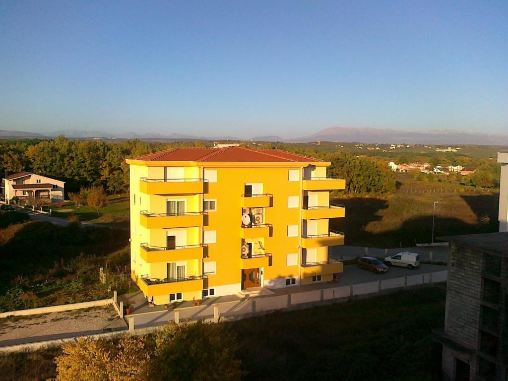 żółty budynek apartamentowy z czerwonym dachem w obiekcie Judita Apartments & Rooms w Medziugorie