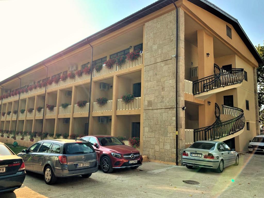 un bâtiment avec des voitures garées devant lui dans l'établissement Hotel Pinguin, à Eforie Nord